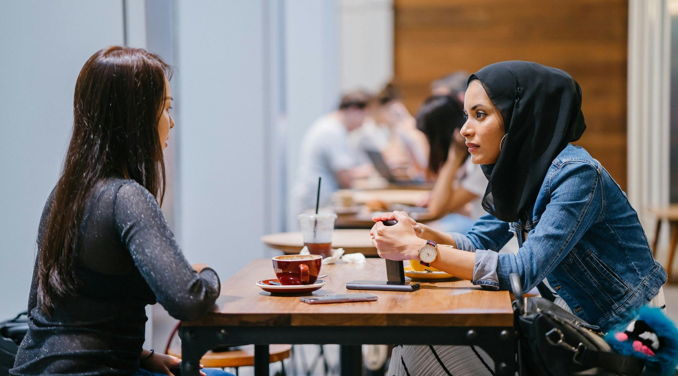 To damer snakker sammen over en kopp kaffe